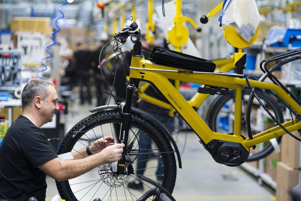 Operario con rueda de bicicleta en soporte amarillo